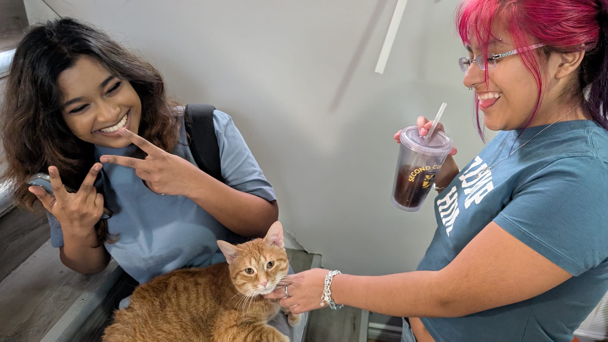 Taniya smiling with a friend and a cat